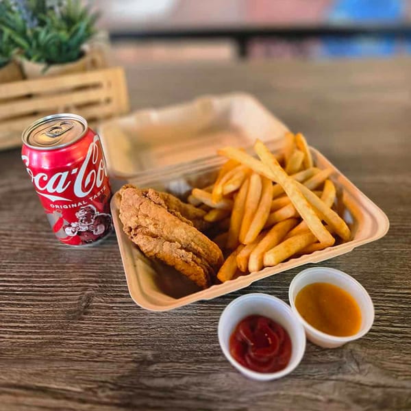 A takeout container with fried chicken tenders and french fries, a Coca-Cola can, and two dipping sauces.