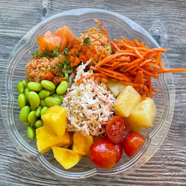 A vibrant poke bowl from Ye's Poke Station, filled with salmon, edamame, mango, and other fresh toppings.