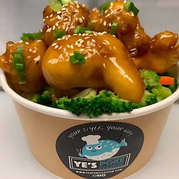 Ye's Poke Station bowl with orange chicken, broccoli, carrots, sesame seeds, and green onions.